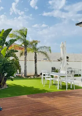 a white table and chairs on a lawn with palm trees at Rosalia Homestay - Ponente Apartment in Cinisi