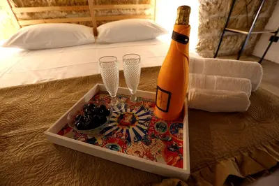 a bottle of champagne and two wine glasses on a bed at Il Siciliano home in Palermo