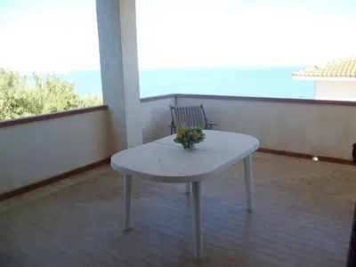 a white table on a balcony with a view of the ocean at LA FINESTRA SUL MARE in Trappeto
