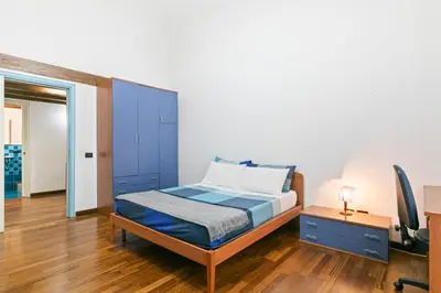a bedroom with a blue bed and a desk at Vittorio Emanuele & Via Roma Colorful Apartment in Palermo