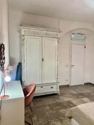 a white cabinet in a room with a desk and a chair at Casa Raffadali, in centro storico a Palermo in Palermo