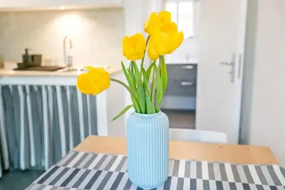 a blue vase with yellow flowers sitting on a table at GuestHost - Stylish Flat Maqueda in Palermo