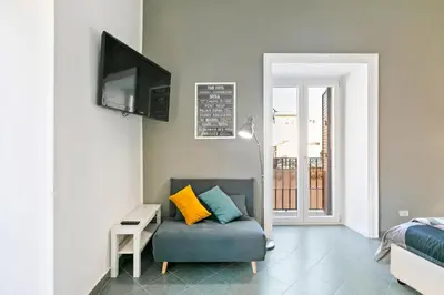 a living room with a couch and a television at GuestHost - Stylish Flat Maqueda in Palermo