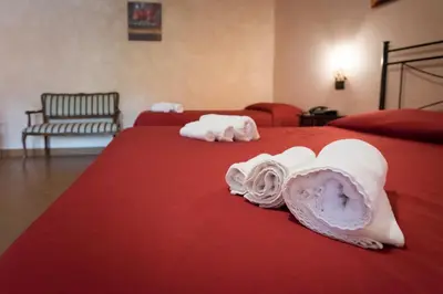 two beds with red sheets with towels on them at Valle Himara in Piana degli Albanesi