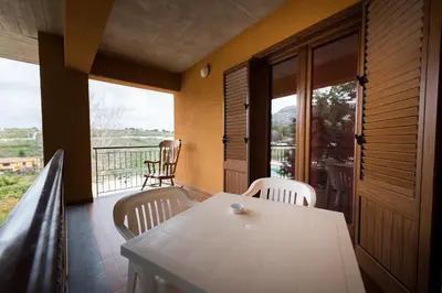 a porch with a white table and chairs on a balcony at Valle Himara in Piana degli Albanesi