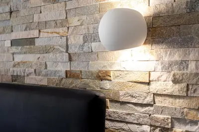 a room with a stone wall with a light fixture at Maqueda House in Palermo