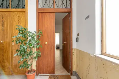 a hallway with a wooden door and a plant at Maqueda House in Palermo