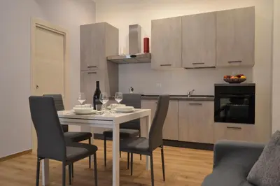 a kitchen with a white table and chairs and a kitchen with cabinets at Appartamento del Golfo in Castellammare del Golfo