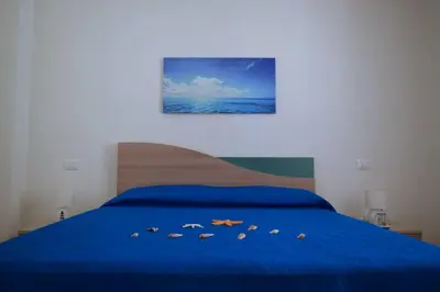 a bedroom with a blue bed with shoes on it at Appartamenti AcquaChiara in San Vito lo Capo