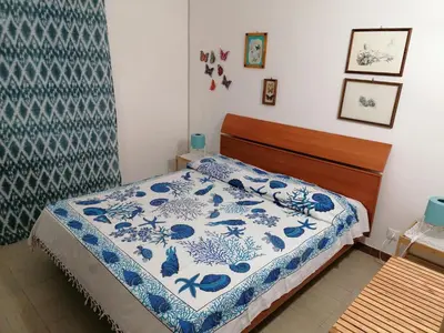 a bedroom with a bed with a blue and white comforter at Apartment in Alcamo near the Beach in Alcamo Marina
