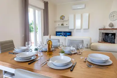 a dining room table with plates and wine glasses at Villa Alma in Campofelice di Roccella