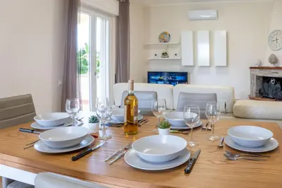 a dining room table with glasses and a bottle of wine at Villa Alma in Campofelice di Roccella