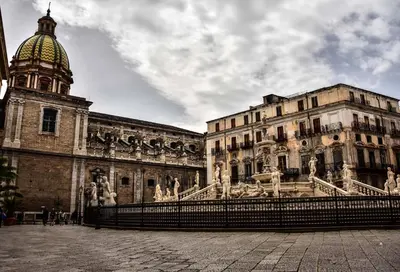 a building with a clock tower and a building with a fountain at Abside Suite & Spa in Palermo