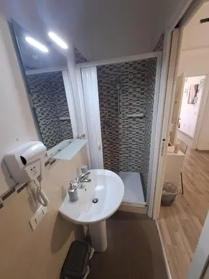 a bathroom with a white sink and a shower at Bedroom la stazione in Palermo