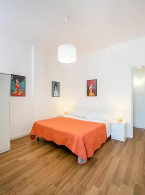 a white bedroom with a bed with an orange blanket at Arricàmpati Villa & Bringo Car Rental in Carini