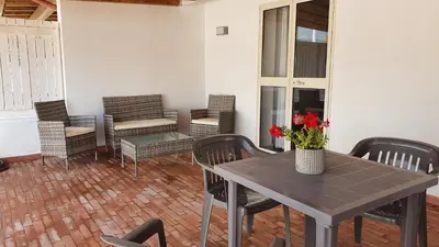a table and chairs on a patio with a table and flowers at Arricàmpati Villa & Bringo Car Rental in Carini
