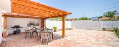 a patio with a wooden pergola and a table and chairs at Arricàmpati Airport Rooms in Villa & RENT CAR in Carini