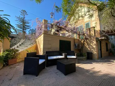 a patio with chairs and tables in front of a building at mondello beach luxury apartments in Palermo