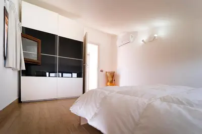 a white bedroom with a bed and a tv at B&B Kòre in Castellammare del Golfo