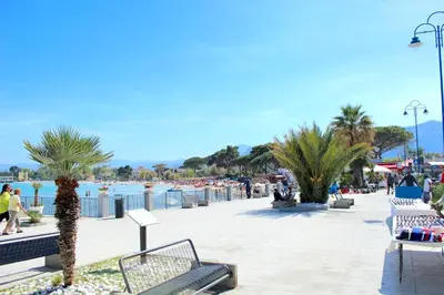 a park with benches and palm trees next to the water at Sicilia d'Amare in Capaci