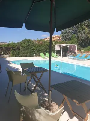 a table and chairs with an umbrella next to a swimming pool at Villa Flore - Penthouse - apartment in villa in Casteldaccia