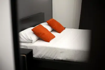 a bed with two orange pillows on it in a mirror at Suites Central Station in Palermo