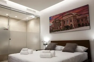 a bedroom with two beds and a painting on the wall at Suites Central Station in Palermo