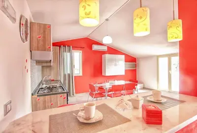 a kitchen with red walls and a table with dishes on it at Case Vacanze Mare Nostrum - Villas in front of the Beach with Pool in Campofelice di Roccella