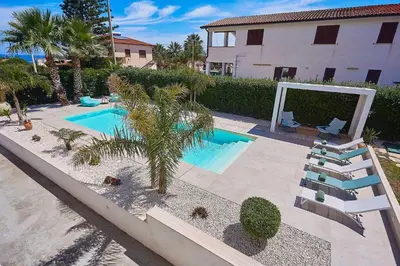 a swimming pool with lounge chairs and a palm tree at Villa Ciuridda in Alcamo