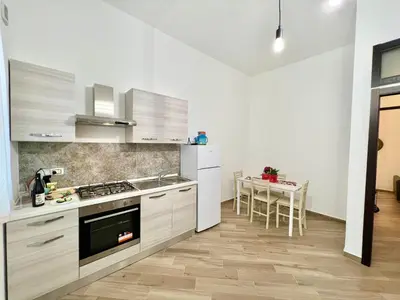a kitchen with white cabinets and a table with chairs at Ciuri di Sicilia in Capaci