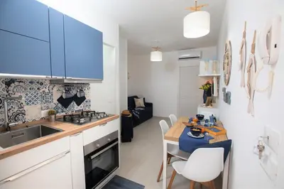 a kitchen with blue cabinets and a table with chairs at Coral Holiday San Vito Lo Capo in San Vito lo Capo