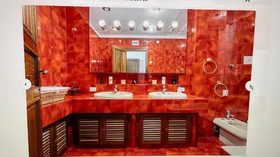 a red tiled bathroom with two sinks and a mirror at CASA DEL CORSO in Cinisi