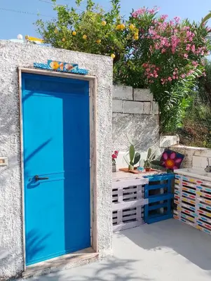 a blue door in a stone wall with flowers at Nuovo AliRu in Campofelice di Roccella