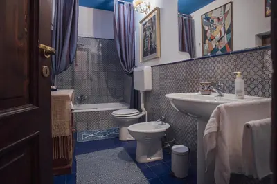 a blue bathroom with a toilet and a sink at Cinematocasa Suite in Palermo