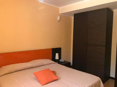 a bedroom with a bed with an orange pillow on it at Castellammare Smart Rooms in Castellammare del Golfo