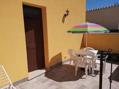 a patio with a table and a colorful umbrella at Appartamento a San Vito lo capo in San Vito lo Capo