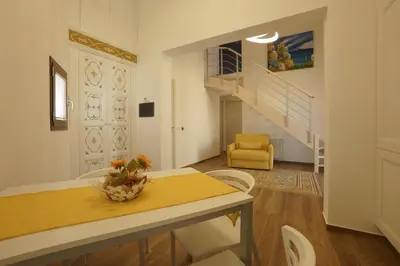 a living room with a table and chairs and a staircase at Stabile HolidayHome in Castellammare del Golfo