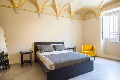 a bedroom with a bed and two tables and a yellow chair at Casa dell'Architetto alla Cattedrale by Wonderful Italy in Palermo