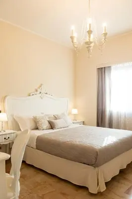a white bedroom with a large bed and a chandelier at Camera Vento Porto Antico La Cala in Palermo