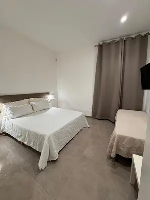 a white bedroom with two beds in a room at Palermo Inn in Palermo