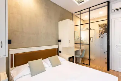 a bedroom with a bed and a desk and a chair at Villena Plaza by Wonderful Italy in Palermo