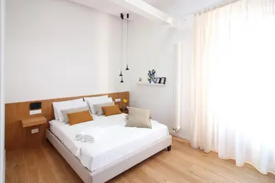 a white bedroom with a large white bed and a window at Pànto - Rooftop boutique rooms in Palermo
