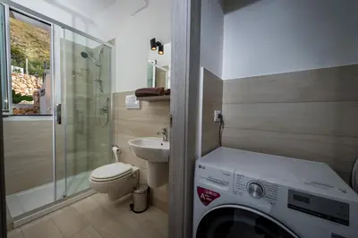 a bathroom with a washing machine and a toilet at Giardino degli Allori - Villa Flores in Castellammare del Golfo