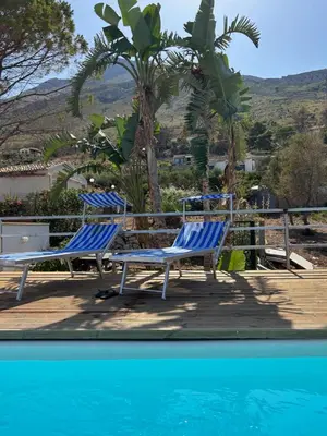two blue chairs sitting next to a swimming pool at Villa Costanza in San Vito lo Capo