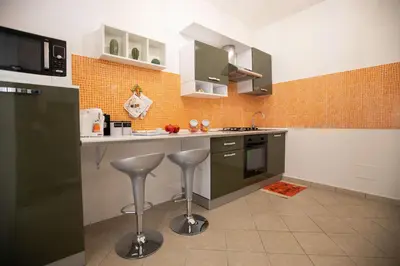 a kitchen with green cabinets and stools in it at La casa di Nana’ locazione turistica in Palermo
