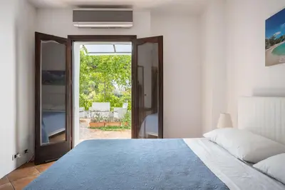 a bedroom with a bed and a view of a patio at Villa a 300 Mt. dal Mare (Magaggiari) con campo da tennis in Cinisi