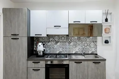 a kitchen with white cabinets and a stove top oven at Little House ai Tartari in Palermo