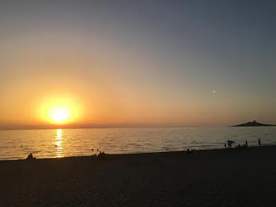 a sunset on the beach with people on the beach at Casa Vacanza La Isla Bonita in Isola delle Femmine