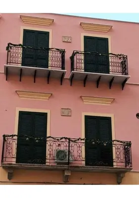 a pink building with black windows and balconies at Appartamento centralissimo in Castellammare del Golfo