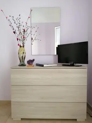 a dresser with a television and a vase with flowers on it at Appartamento centralissimo in Castellammare del Golfo